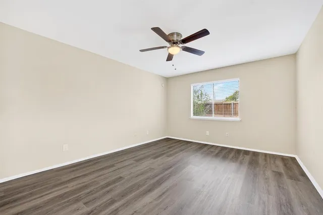 an empty room with wooden floor fan and windows