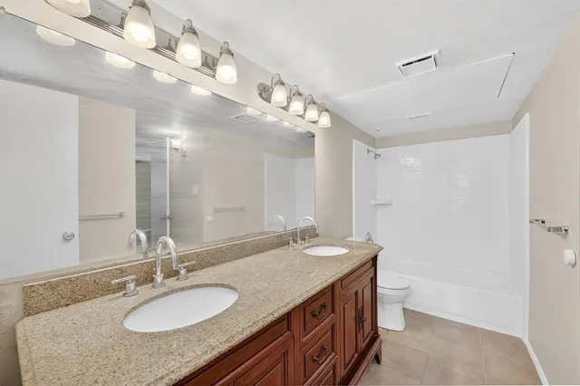 a bathroom with a granite countertop double vanity and a mirror