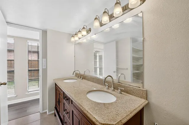 a bathroom with a granite countertop double vanity and a mirror