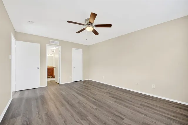 a view of empty room with wooden floor and ceiling fan