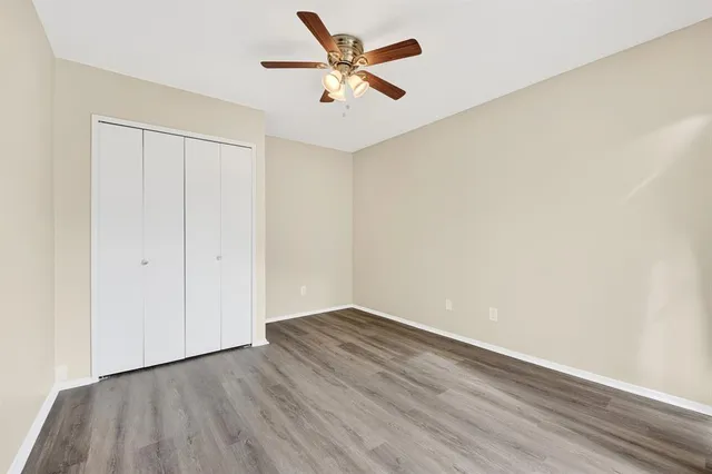 an empty room with wooden floor and a ceiling fan