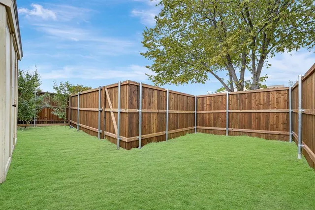 a view of a backyard with wooden fence and a large tree