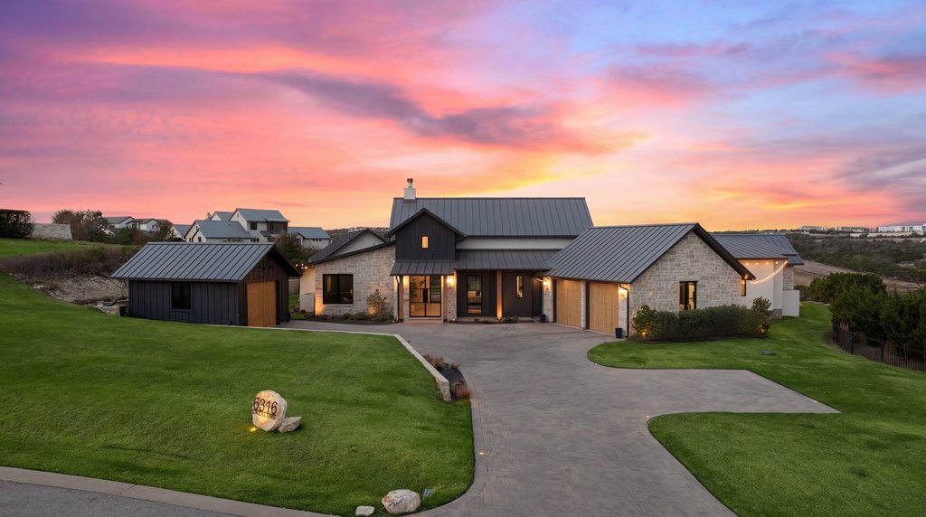 Modern inspired farmhouse featuring a standing seam roof, a front lawn, driveway, and a chimney