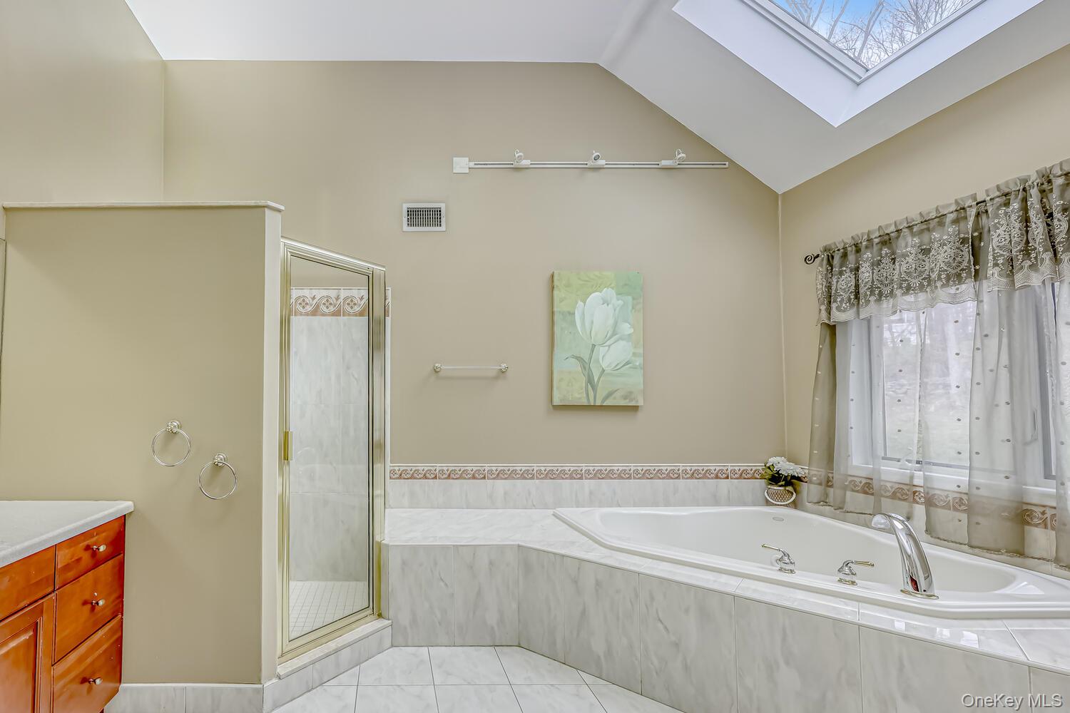 22 Golden Road Suffern, NY 10901 - Photo 32 of 41 Bathroom featuring a skylight, a bath, a shower stall, light tile patterned floors, and lofted ceiling