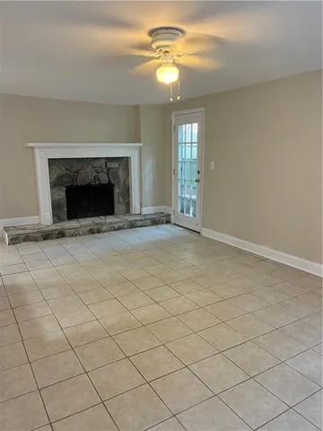 a view of an empty room with chandelier fan and fire place