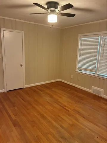an empty room with wooden floor fan and windows