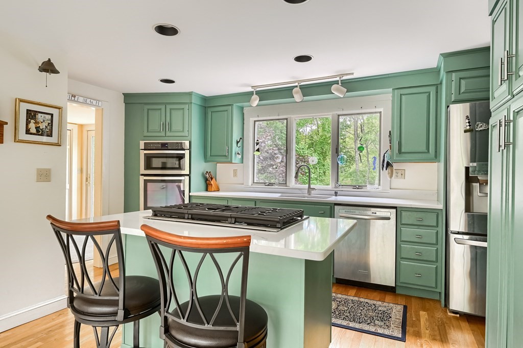 214 Park Avenue Barnstable, MA 02632 - Photo 14 of 42 a kitchen with stainless steel appliances granite countertop a stove a refrigerator a microwave oven with a dining table and chairs with wooden floor