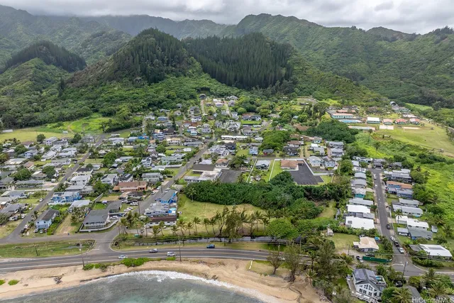 an aerial view of residential house with green space and mountain view in back
