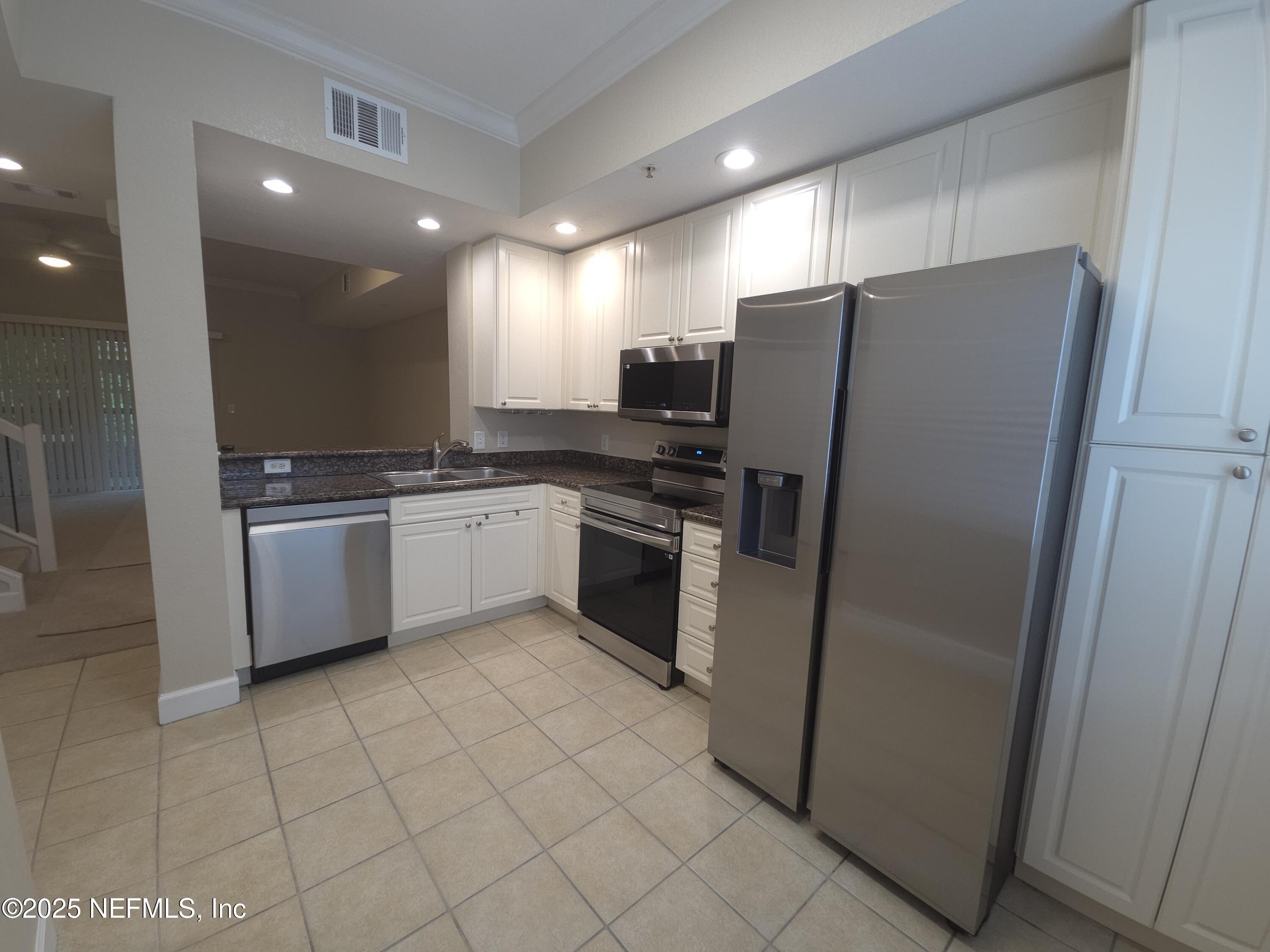 9745 Touchton Road, Unit 427 Jacksonville, FL 32246 - Photo 7 of 52 a kitchen with stainless steel appliances a refrigerator sink and microwave