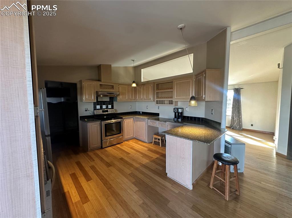33171 Elk Park Road Trinidad, CO 81082 - Photo 4 of 21 a kitchen with granite countertop kitchen island wooden floors stainless steel appliances a sink and a refrigerator