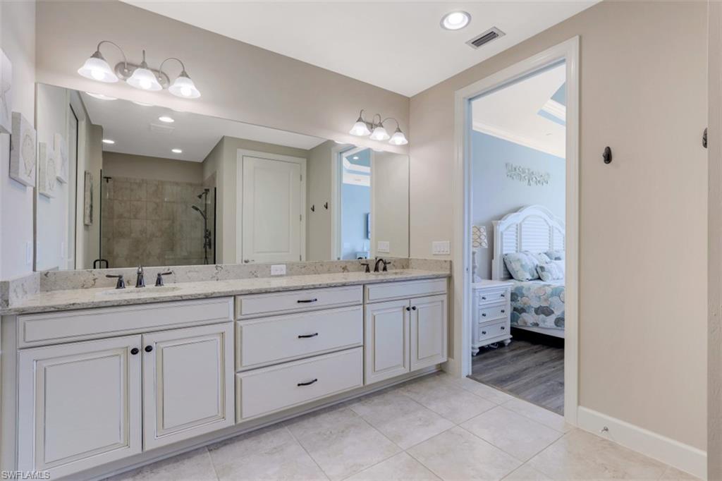 8776 Bellano Court, Unit 104 Naples, FL 34119 - Photo 11 of 34 a spacious bathroom with a double vanity sink and a mirror