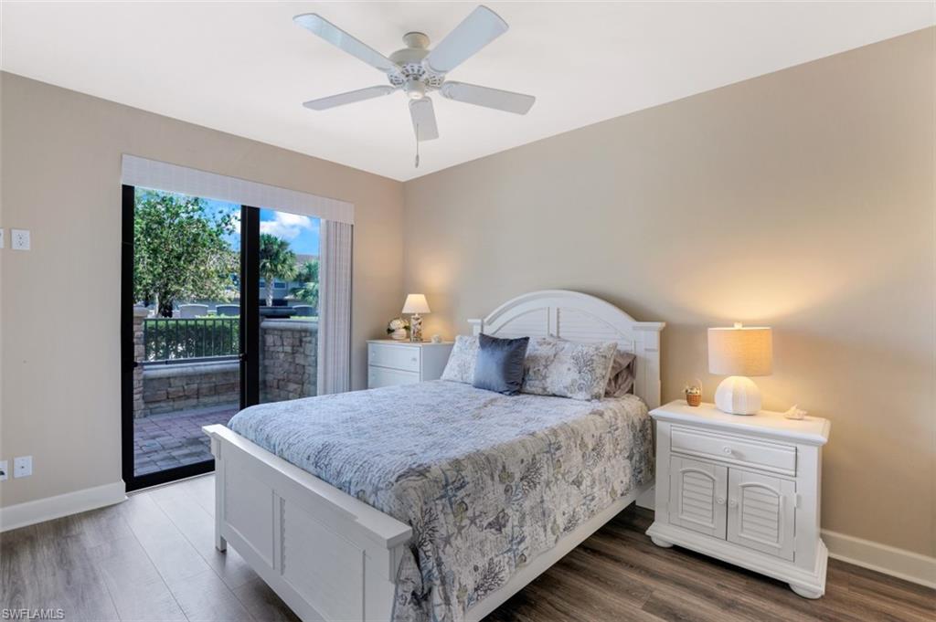 8776 Bellano Court, Unit 104 Naples, FL 34119 - Photo 13 of 34 a bedroom with a large bed and a chandelier