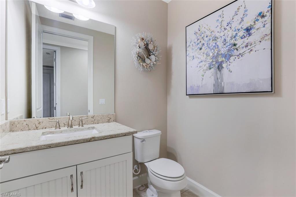 8776 Bellano Court, Unit 104 Naples, FL 34119 - Photo 17 of 34 a bathroom with a granite countertop toilet a sink and a mirror