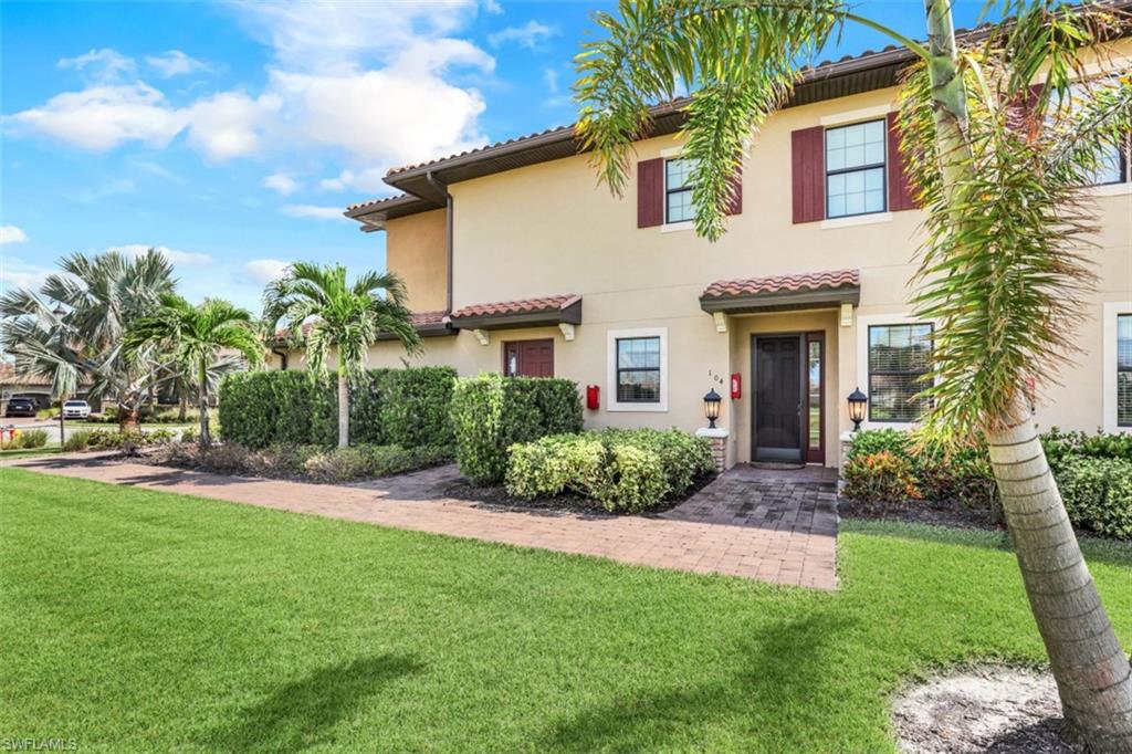 8776 Bellano Court, Unit 104 Naples, FL 34119 - Photo 22 of 34 a front view of a house with a yard and potted plants