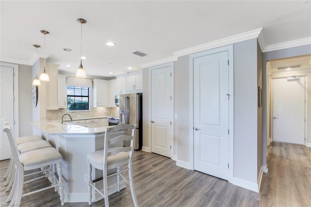 8776 Bellano Court, Unit 104 Naples, FL 34119 - Photo 5 of 34 a kitchen with stainless steel appliances kitchen island wooden floors and white cabinets