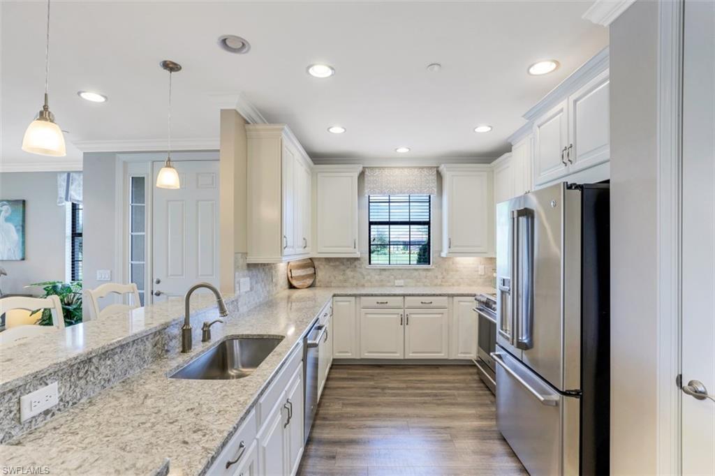 8776 Bellano Court, Unit 104 Naples, FL 34119 - Photo 6 of 34 a kitchen with white cabinets and stainless steel appliances