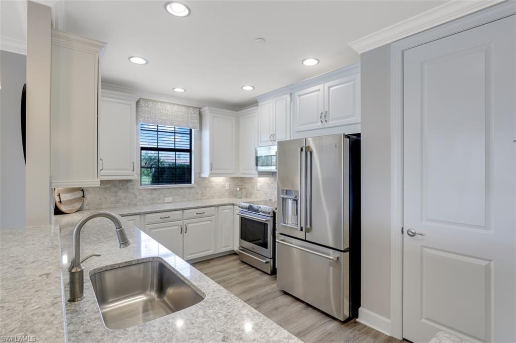 8776 Bellano Court, Unit 104 Naples, FL 34119 - Photo 8 of 34 a kitchen with stainless steel appliances granite countertop a refrigerator sink and stove