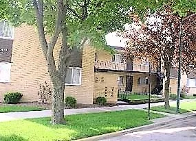 a front view of a house with a garden and tree
