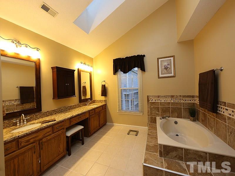 2108 Osprey Circle Raleigh, NC 27615 - Photo 8 of 15 a bathroom with a tub a double vanity sink and mirror