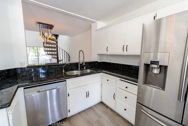 a kitchen with granite countertop white cabinets white stainless steel appliances a sink and a window