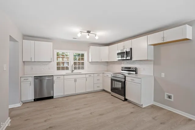 a kitchen with granite countertop white cabinets and stainless steel appliances