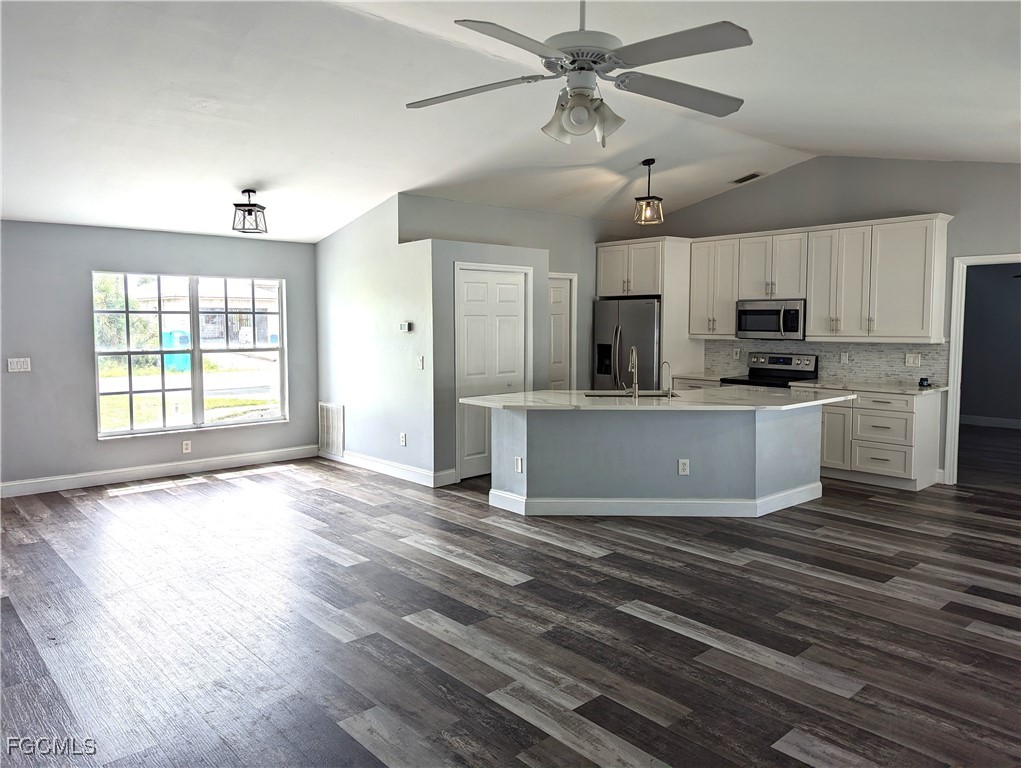 2311 Southwest 16th Terrace Cape Coral, FL 33991 - Photo 8 of 23 a view of a kitchen with a sink a refrigerator a ceiling fan and wooden floor