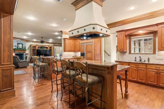 a kitchen with stainless steel appliances kitchen island granite countertop a table chairs in it and wooden floors