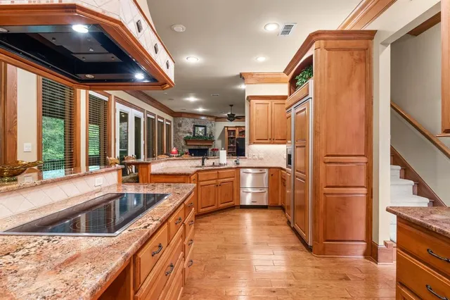 a kitchen with stainless steel appliances granite countertop a refrigerator a stove and a sink with wooden floor