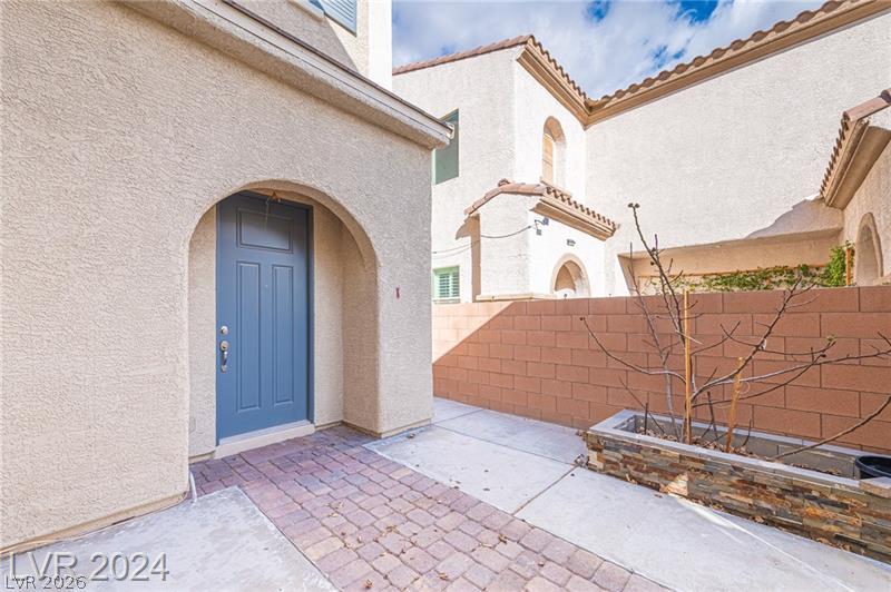 9056 Tony Ridge Avenue Las Vegas, NV 89148 - Photo 3 of 32 A welcoming arched entryway leads to a vibrant blue door, accented by a decorative stone planter.
