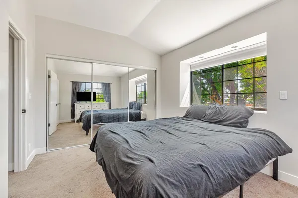 a bedroom with a bed large mirror and a large window