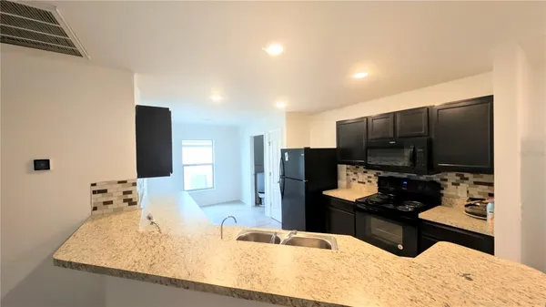 a kitchen with stainless steel appliances kitchen island granite countertop a refrigerator and a sink