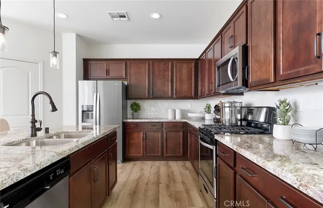 a kitchen with granite countertop a sink stainless steel appliances and cabinets