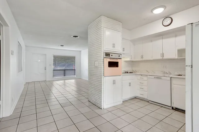 a kitchen with white cabinets a sink dishwasher and a stove with wooden floor