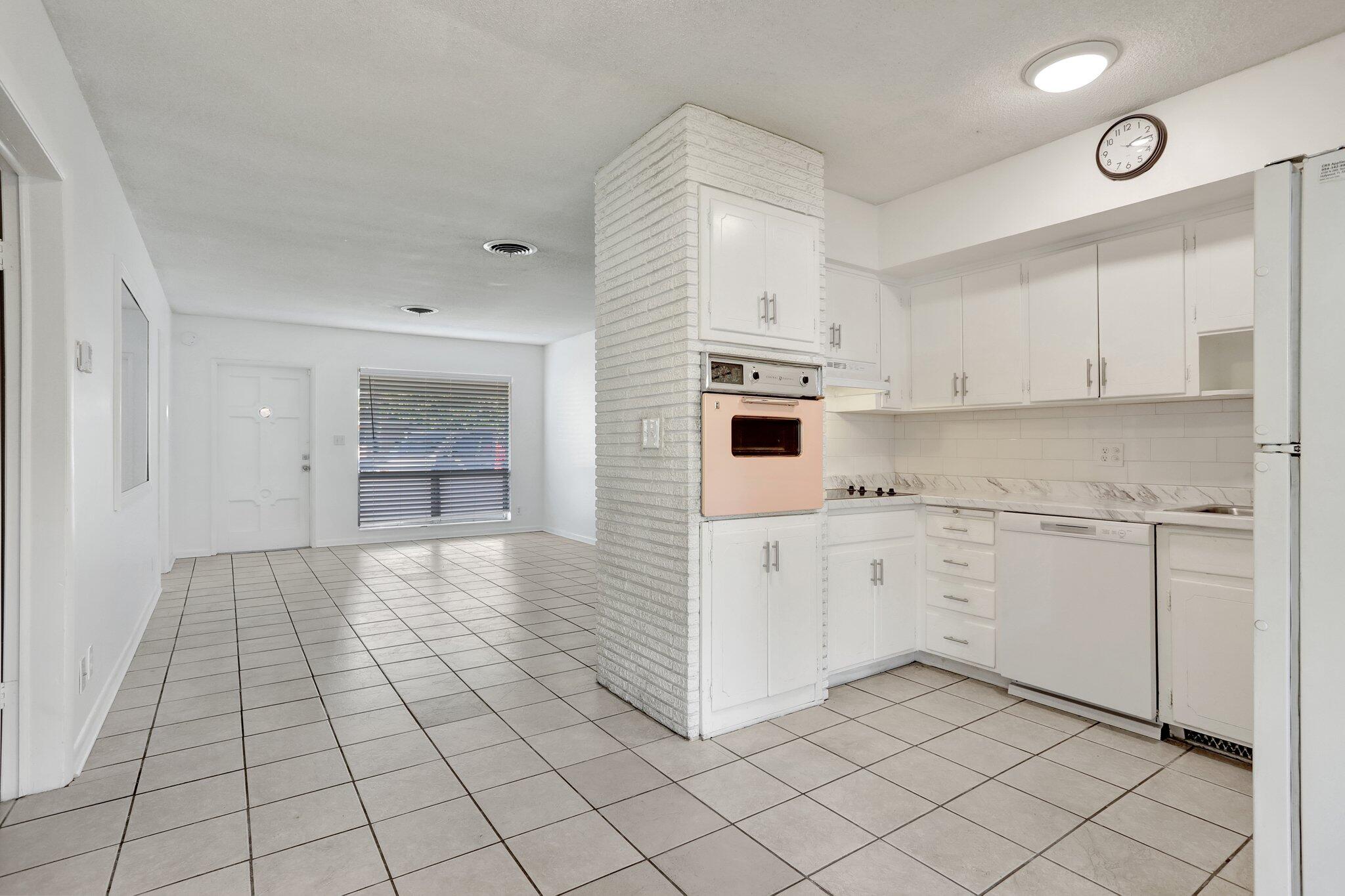 2540-2550 Northeast 10th Court, Unit 12 Pompano Beach, FL 33062 - Photo 14 of 25 a kitchen with white cabinets a sink dishwasher and a stove with wooden floor