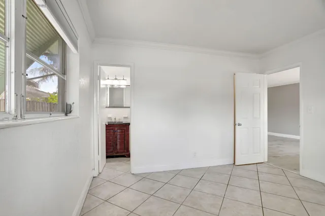 a view of an empty room with window and chandelier fan