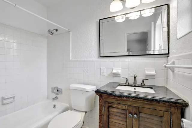 a bathroom with a granite countertop sink a toilet and a mirror