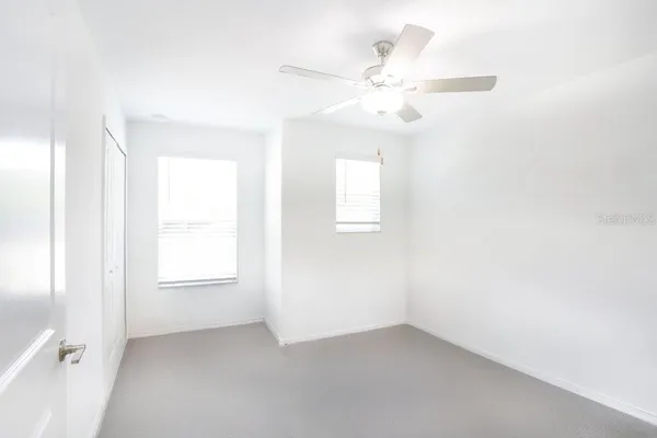 an empty room with windows and fan