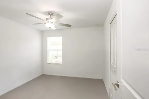 an empty room with windows and fan
