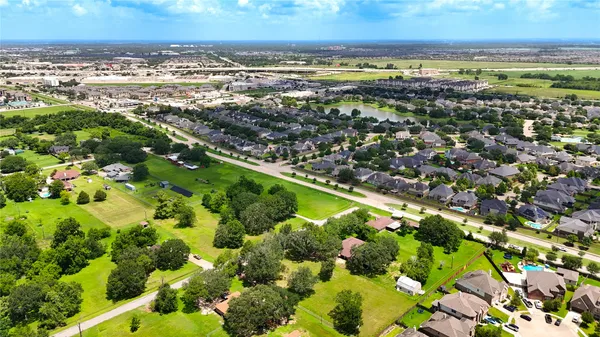 an aerial view of residential houses with outdoor space and trees