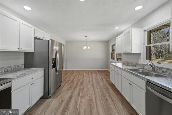a kitchen with stainless steel appliances granite countertop a refrigerator sink and wooden cabinets