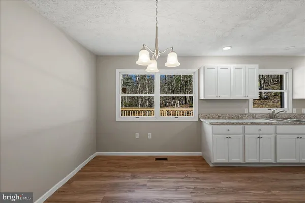 a view of kitchen with granite countertop cabinets a sink and a wooden floor