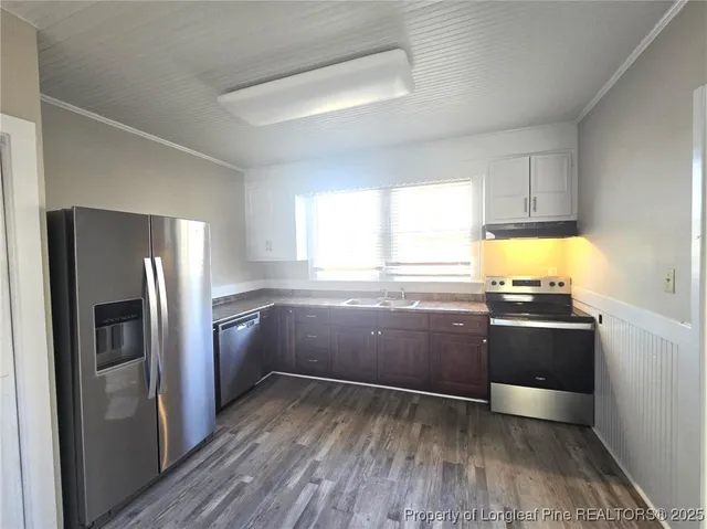 a kitchen with granite countertop a refrigerator and wooden cabinets