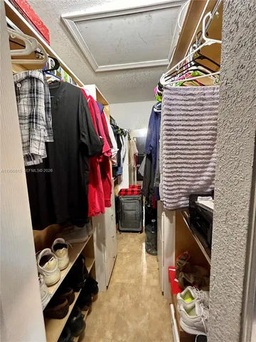 a view of walk in closet with clothes and shoes