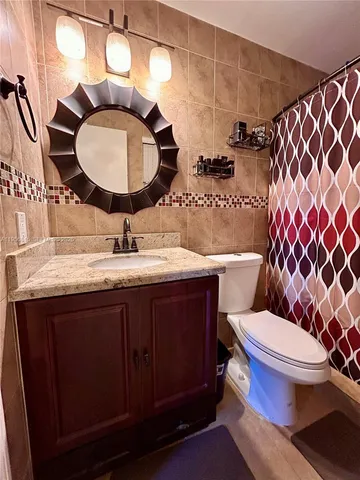 a bathroom with a granite countertop toilet sink and mirror