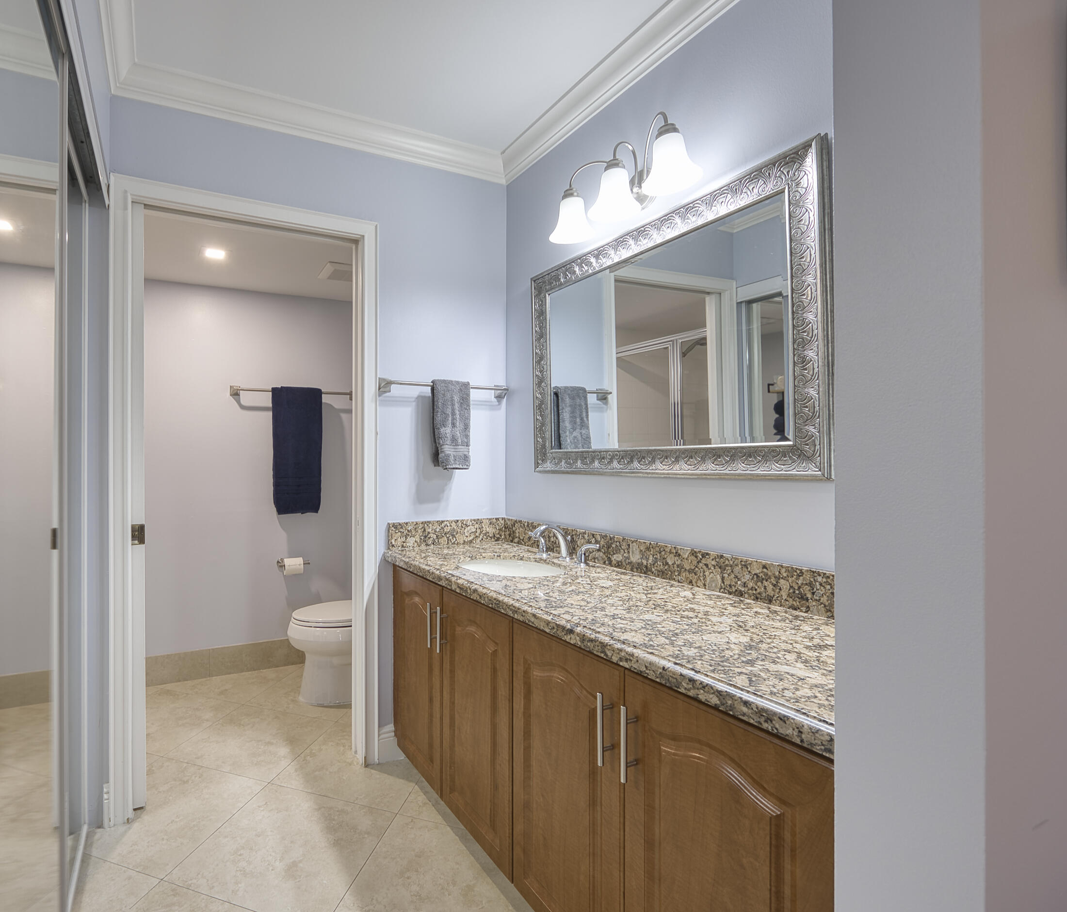 380 Northwest 67th Street, Unit 101 Boca Raton, FL 33487 - Photo 23 of 44 a bathroom with a granite countertop sink a toilet and mirror