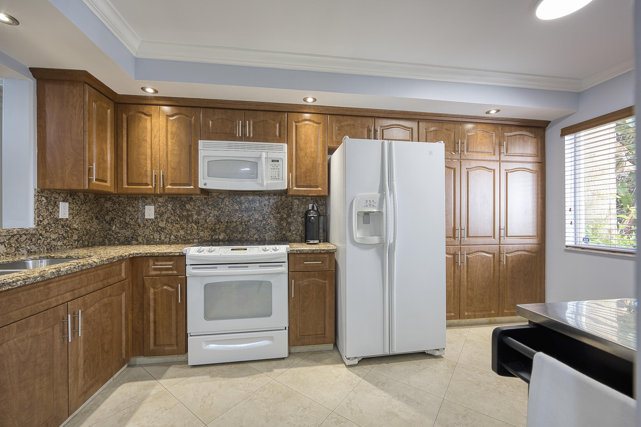 380 Northwest 67th Street, Unit 101 Boca Raton, FL 33487 - Photo 8 of 44 a kitchen with stainless steel appliances granite countertop a refrigerator and a stove top oven