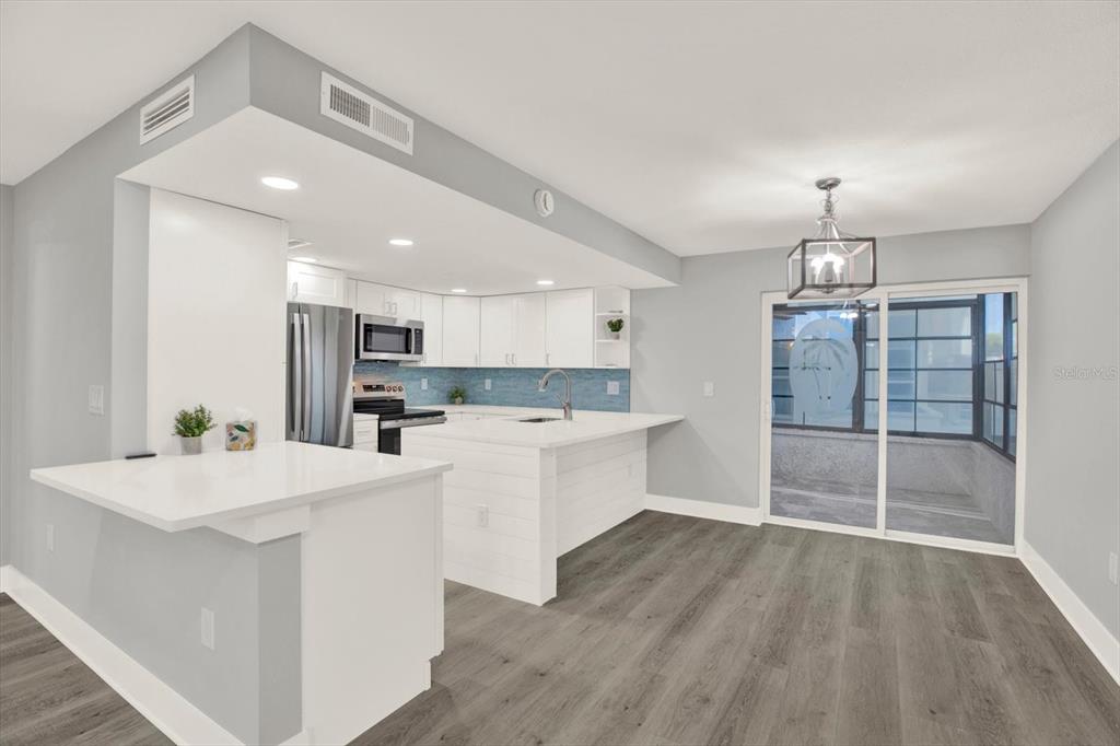 337 Rex Place, Unit A Madeira Beach, FL 33708 - Photo 15 of 48 a large white kitchen with wooden floor and stainless steel appliances