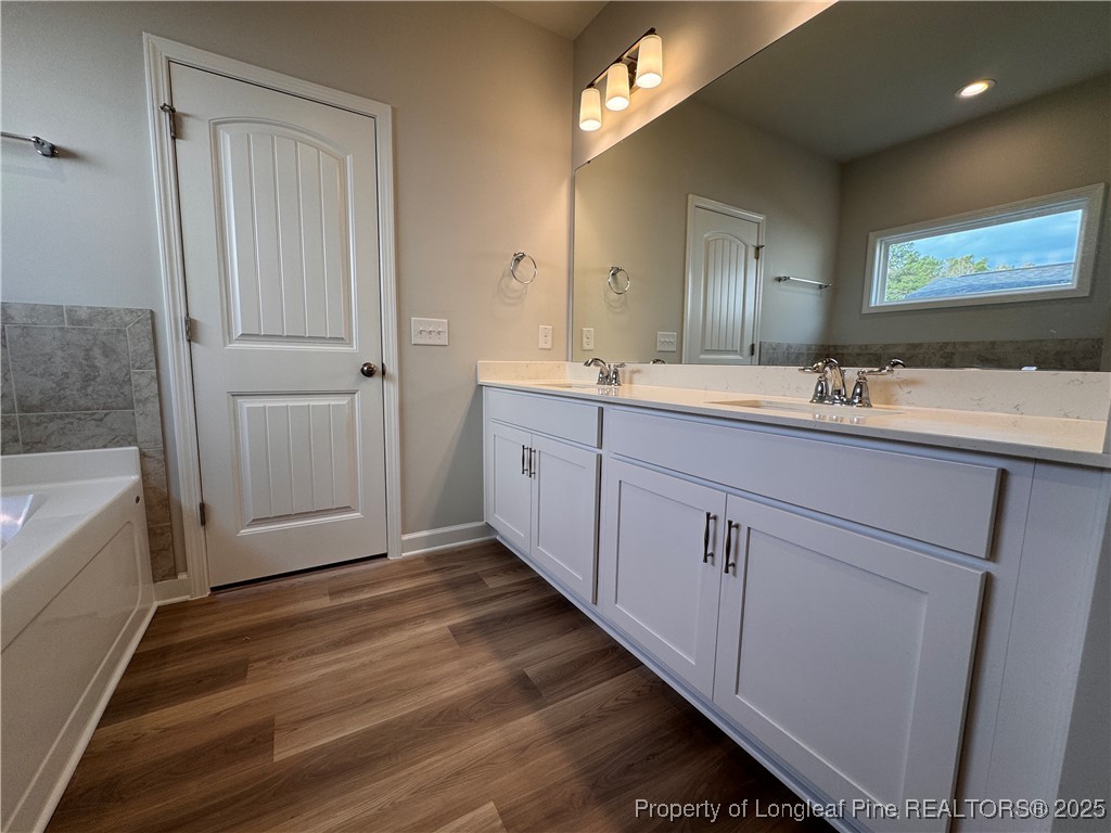 294 Elijah Way Vass, NC 28394 - Photo 20 of 33 a bathroom with a double vanity sink a mirror and a bathtub