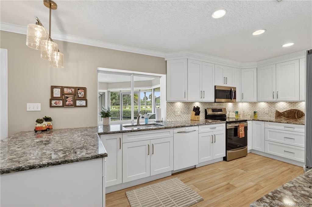 3353 Southeast Fairway East Stuart, FL 34997 - Photo 8 of 55 a kitchen with stainless steel appliances granite countertop a stove top oven a sink dishwasher and a refrigerator with wooden floor