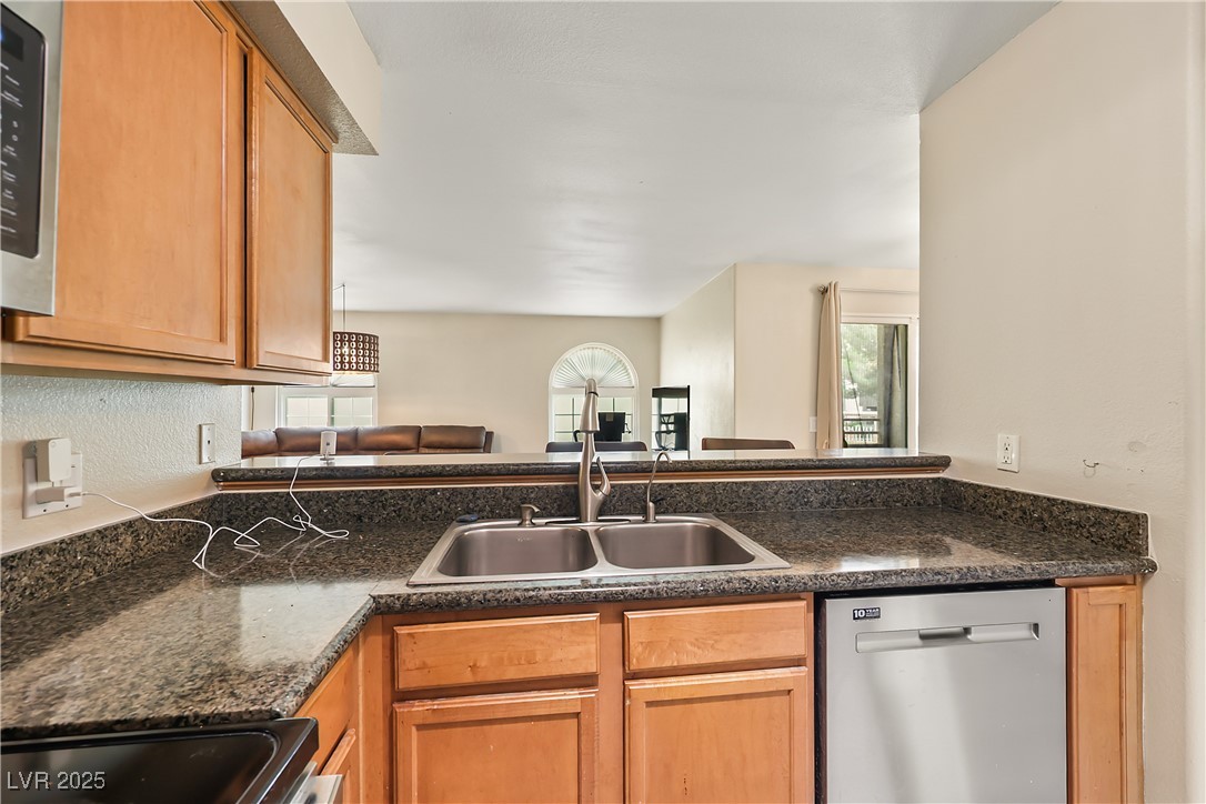 3145 East Flamingo Road, Unit 1123 Las Vegas, NV 89121 - Photo 12 of 30 Kitchen with stainless steel dishwasher, stove, brown cabinets, and a peninsula